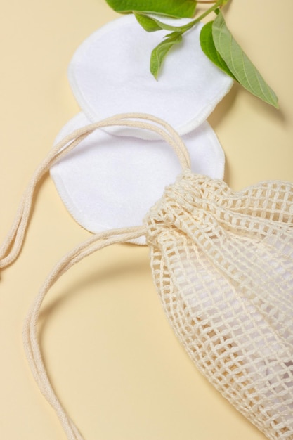 Cotton reusable makeup remover pads in a cloth bag on a beige background The concept of ecology and conscious consumption Reusable cotton pads