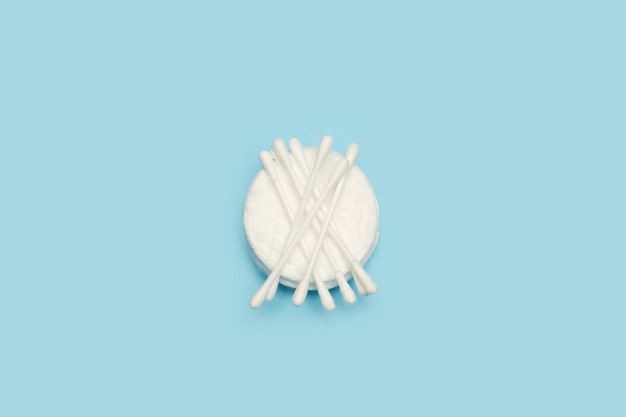 Cotton swabs and round cotton pads on a light blue background with copy space