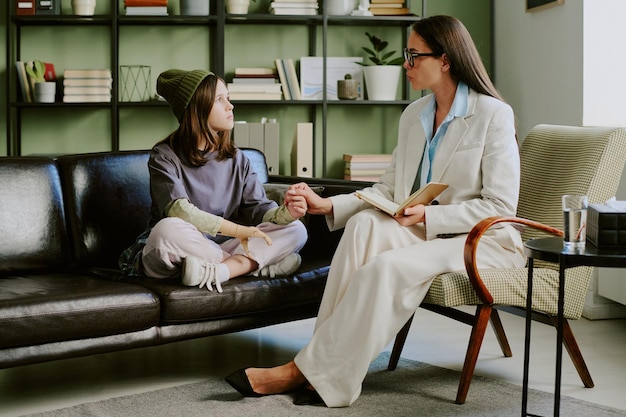 Photo counselor assisting child on comfortable couch during session