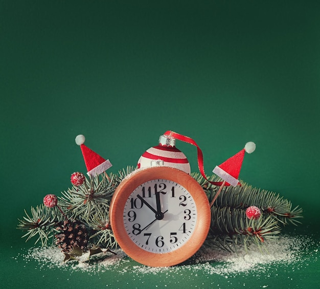 Countdown to midnight wood alarm clock with red baubles santa hats berries fir twigs green paper