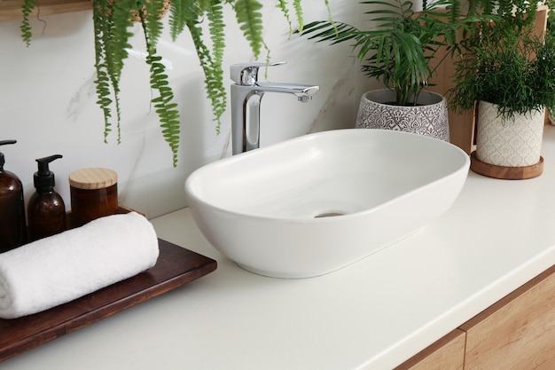 Counter with sink and many different houseplants near white marble wall