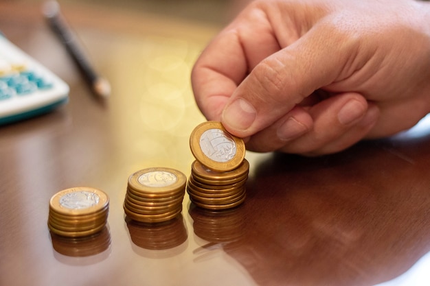 Counting brazilian money, real coins. Calculator and pen in blurred background.