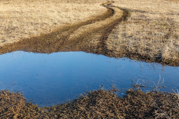 Country road in early spring season mud and puddle