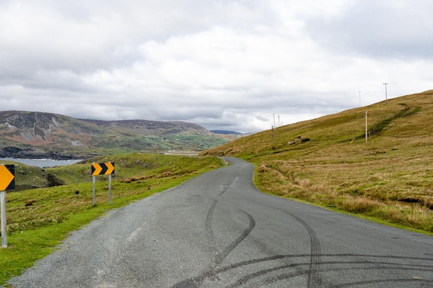 A country road with tire marks left on the side of it.