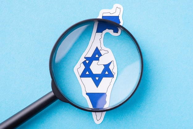 Country studying of Israel. Magnifying glass on map of Israel on blue background