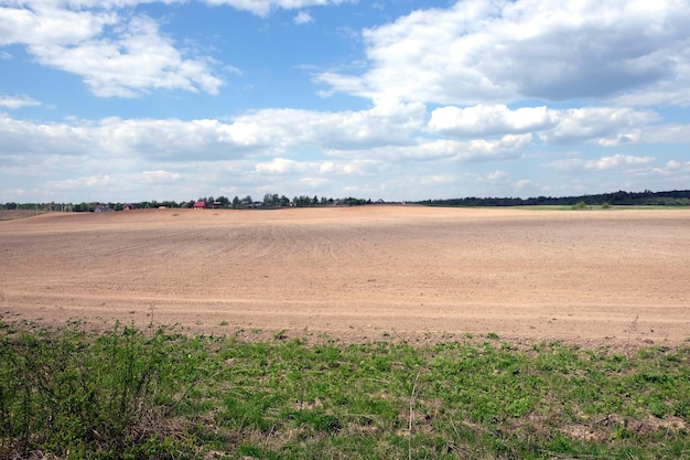 Countryside landscape with plowed field and a village far away on spring day