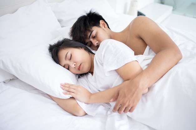 Couple Asian man and woman on bed in white bedroom