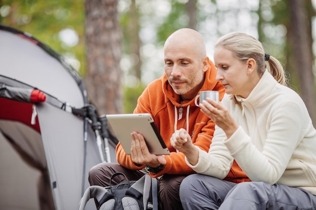 Couple of backpackers looking on tablet computer