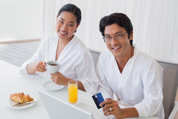 Couple in bathrobes shopping online in the morning