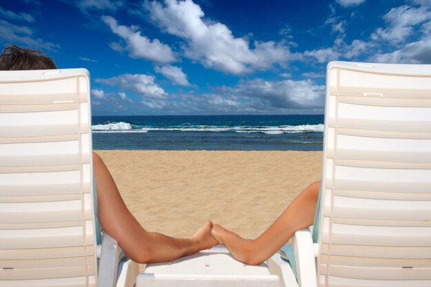 Couple in beach chairs holding hands near ocean