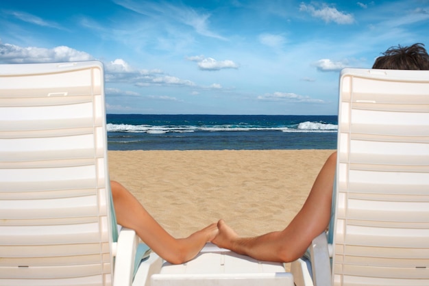 Couple in beach chairs holding hands near ocean