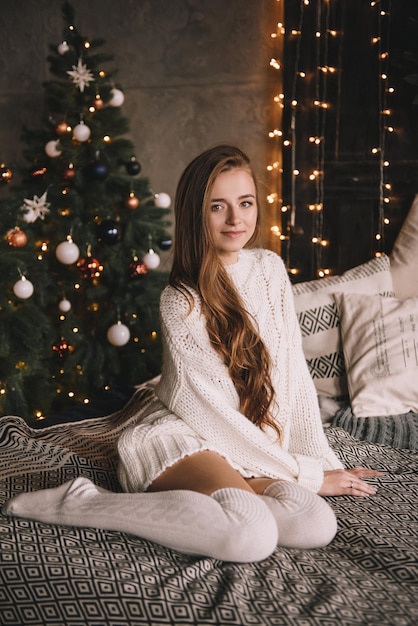 Couple on the bed in the bedroom. Dark interior. New Year's and Christmas. Hugs and kisses. Love. White sweater and high socks. Romantic meeting. A date lovers.