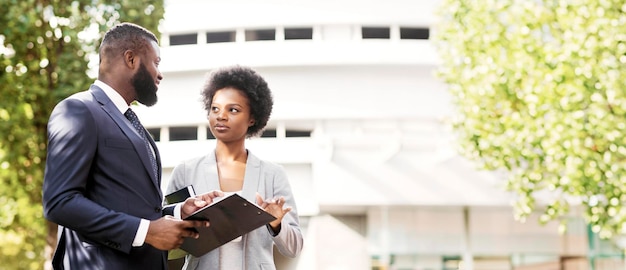 Couple of black business partners checking office documentation outdoors