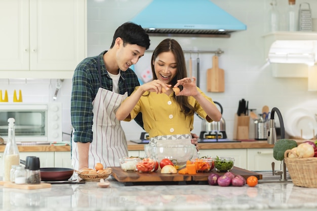 A couple breaks an egg to make a morning omelet at home