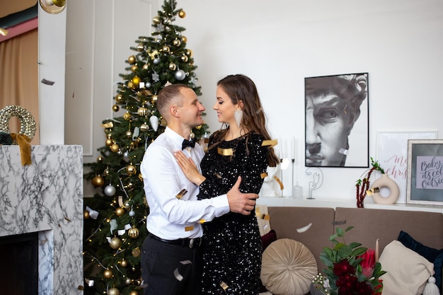 Couple celebrating christmas and holidays happily near beautifully decorated christmas tree christmas concept