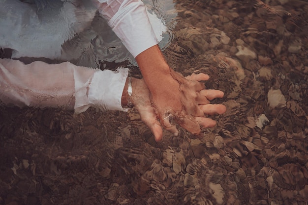 A couple in clothes holding hands in the sea High quality photo