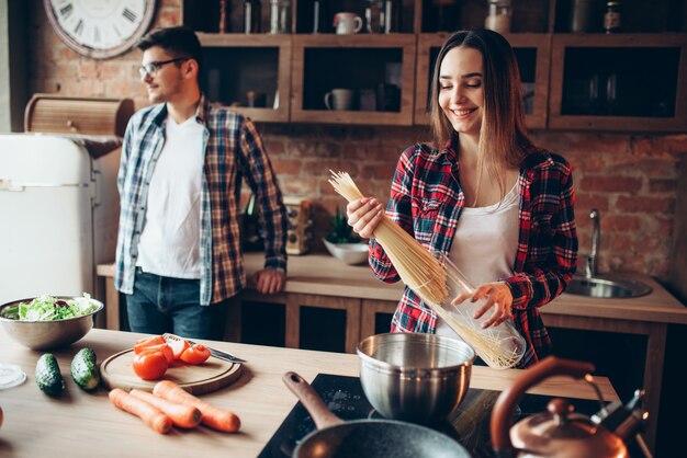 Photo couple cooking fresh vegetable salad and spaghetti