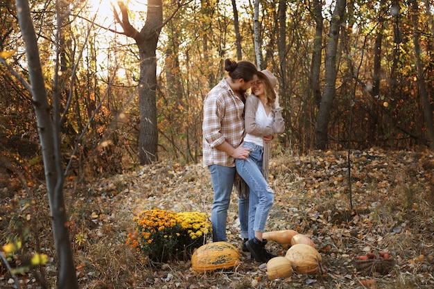 Couple cuddles on a walk in the fall with pumpkins