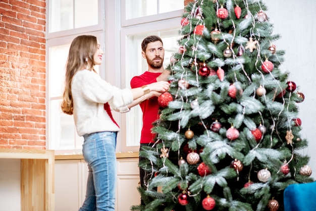 Couple decorating new year tree indoors