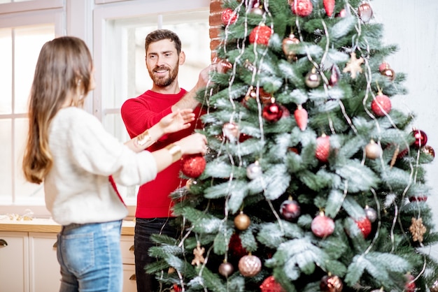 Couple decorating new year tree indoors