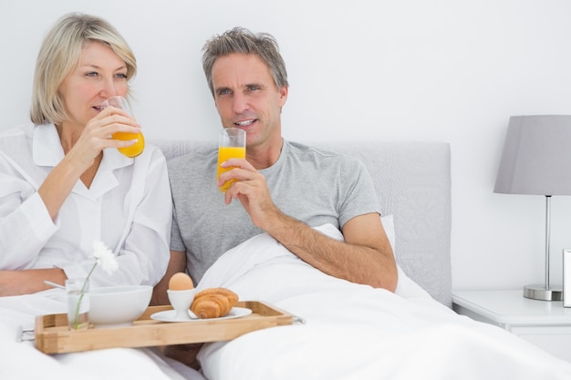 Couple drinking orange juice having breakfast in bed