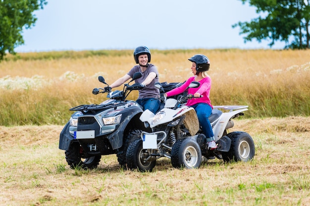 Couple driving off-road with quad bike or ATV