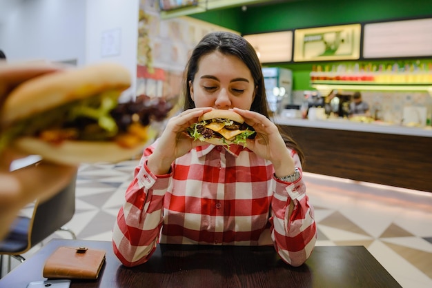 Couple eat cheeseburgers in cafe