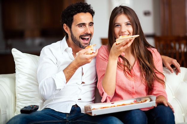 Couple eating pizza and watching TV