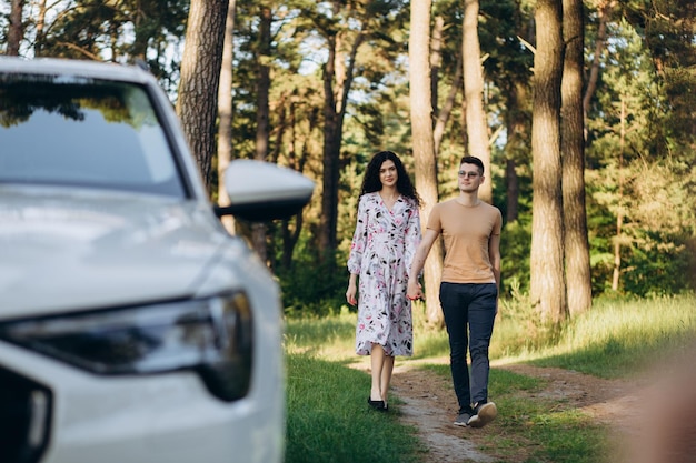 Couple embracing each other in the forest near modern car