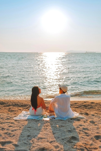 A couple enjoying a beach vacation at a tropical resort with a beautifully landscaped coastal pool at sunset honeymoon destination at Thailand