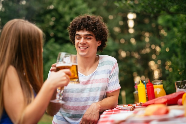 Couple enjoying drinking beer with friends on a picnicl