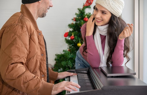 Couple enjoying great time with piano Man playing piano and singing for woman Celebrating winter