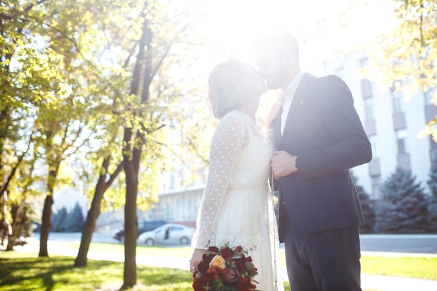 Couple enjoying romantic moments in park Elegant bride in beautiful white dress groom in a suit