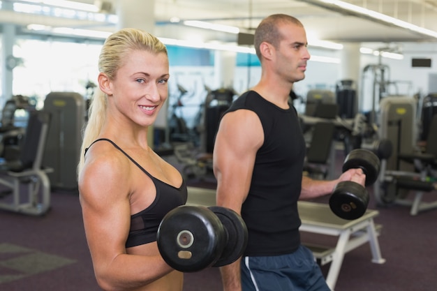 Couple exercising with dumbbells in gym