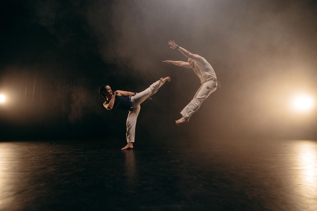 Photo couple of fighters training capoeira on black background