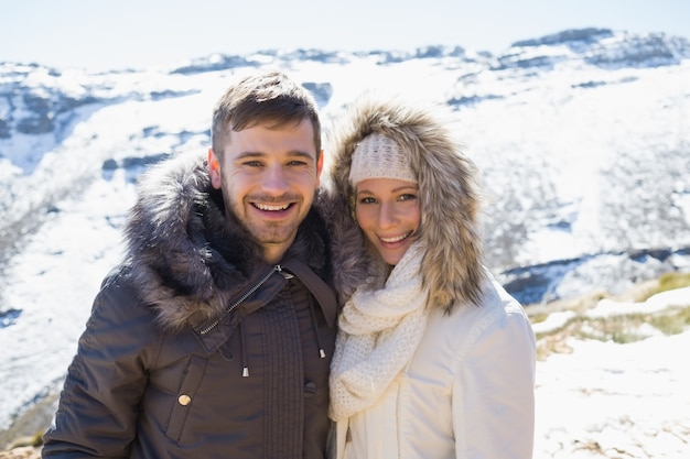 Couple in fur hood jackets against snowed mountain range