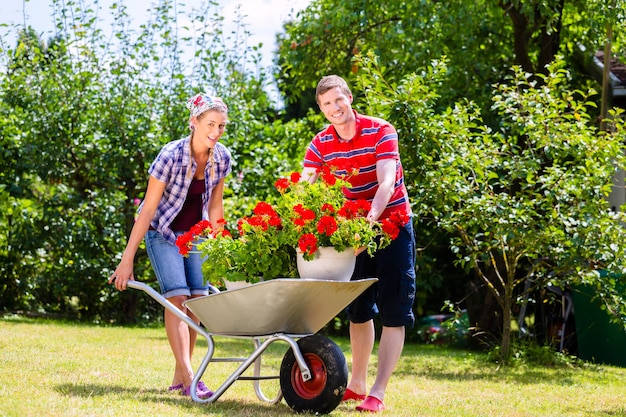 Couple in garden with barrow and flowers working