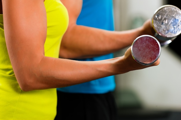 Couple in gym exercising with dumbbells