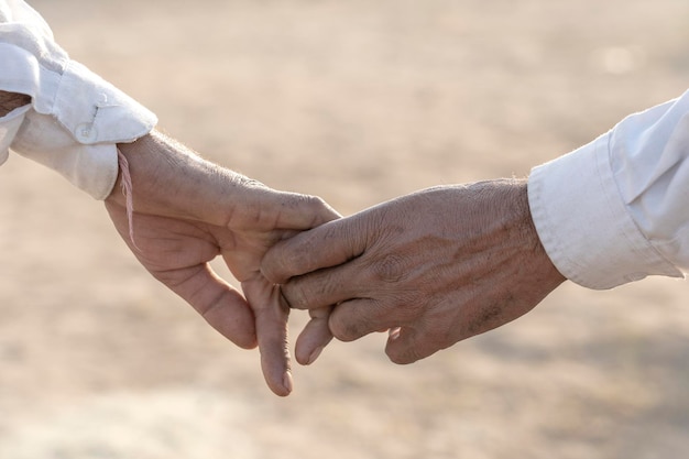 Couple hands on the street during Pushkar Camel Mela near city Pushkar Rajasthan India close up In India it is normal to go to men holding each other by the hand