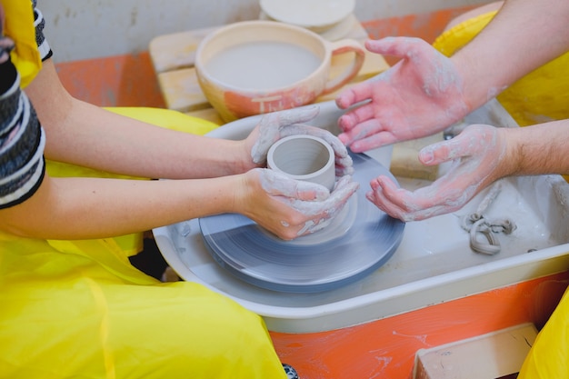 Couple hands working with clay on pottery wheel. Creative romantic date idea