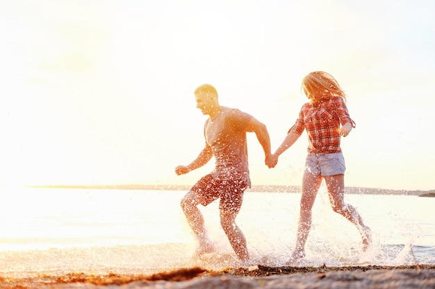 Couple happy on the beach holidays run motion legs sunset splashing water