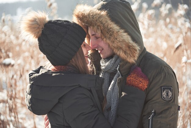 Couple has fun and laughs. kiss. Young hipster couple hugging each other in winter park. Winter love story, a beautiful stylish young couple. Winter fashion  with boyfriend and girlfriend