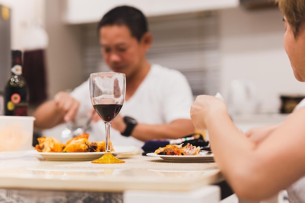 Couple having a dinner with glasses of red wine on table at home