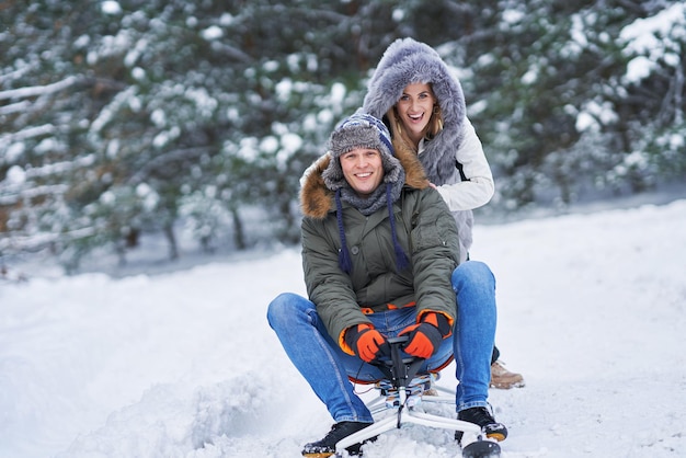 Couple having fun with sledge on snow in winter snow. High quality photo