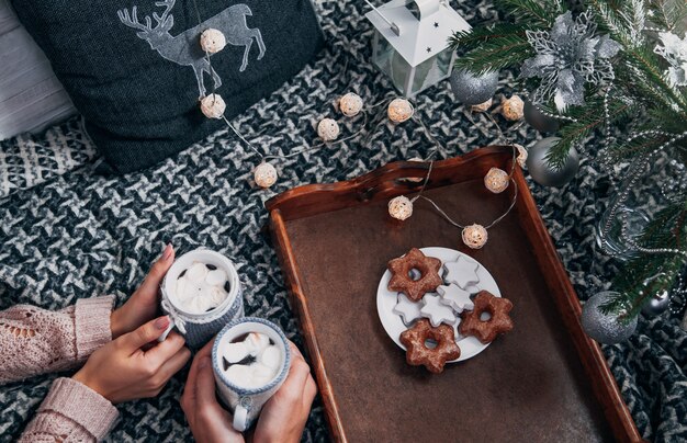 Photo couple having hot chocolate with biscuits under the christmas tree