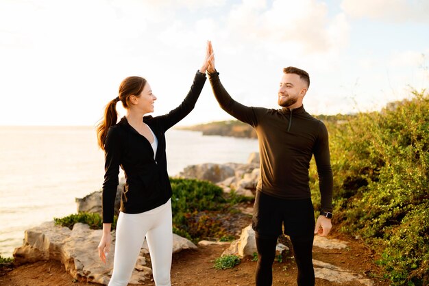 Photo couple highfiving during sunset workout by the sea