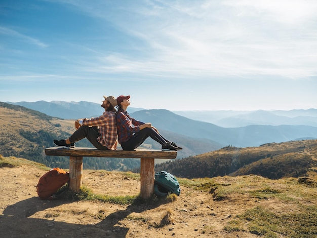 Couple of hikers with backpacks in front of landscape valley view on top of a mountain