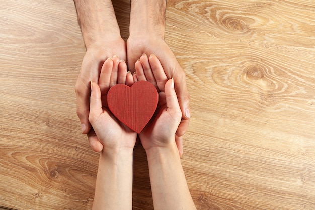 Couple hold wooden heart. view from above