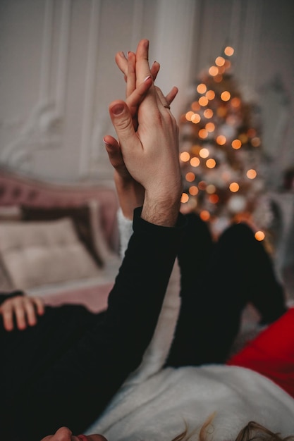 a couple holding hands on the background of a Christmas tree