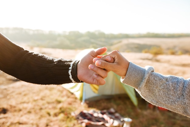 Couple holding hands near the tent. cropped image